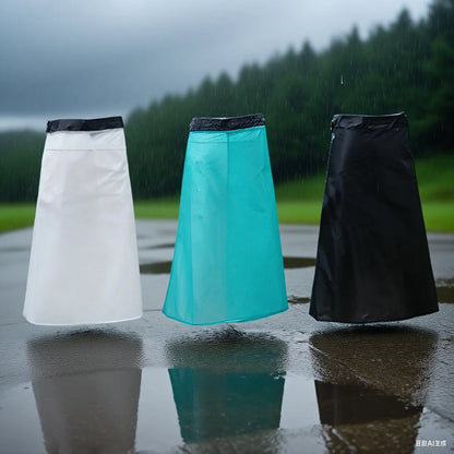 Three raincoats in white, turquoise, and black standing on a wet surface with a rainy background.