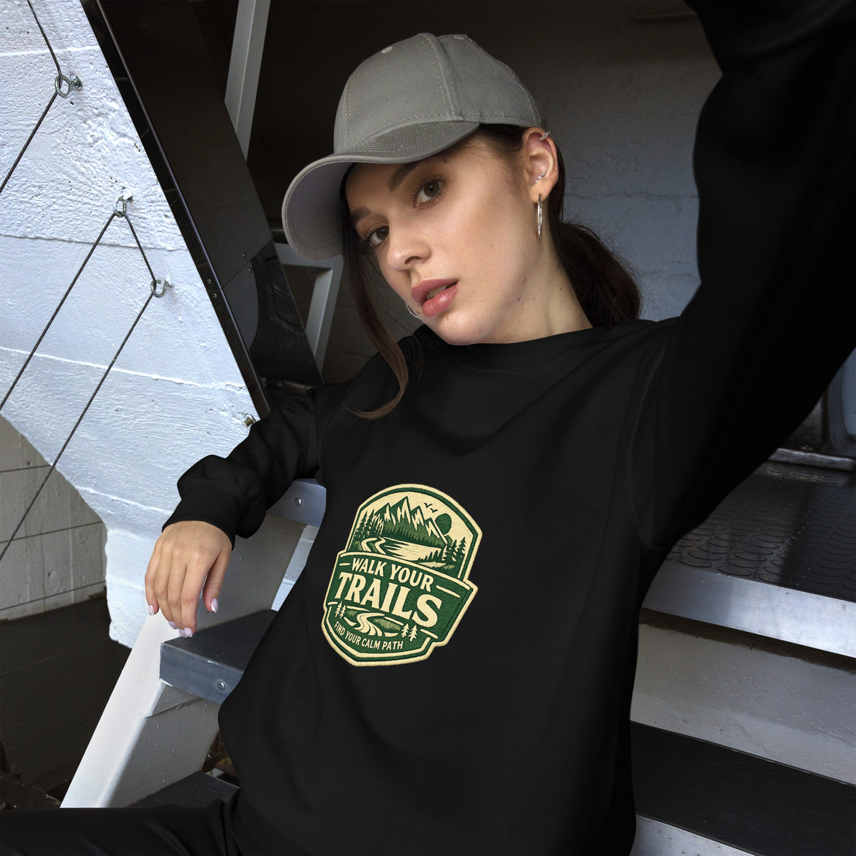 Comfortable Sweatshirt, Person wearing a black hoodie with a green logo and text, sitting on steps.