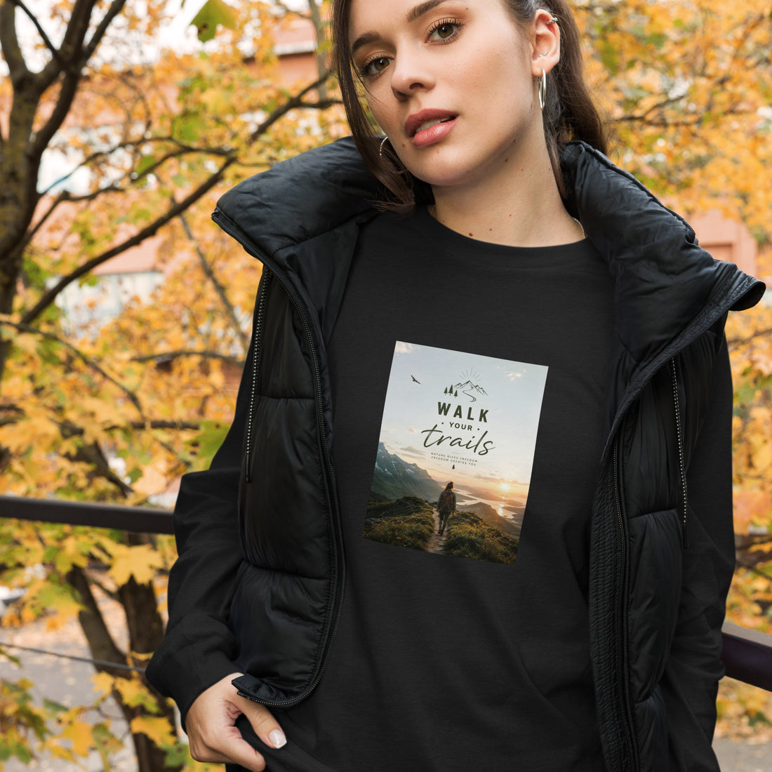 Unisex Long Sleeve Tee, Woman wearing a black jacket with a scenic t-shirt design outdoors in autumn.