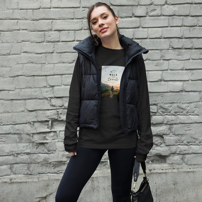 Unisex Long Sleeve Tee, Woman wearing a black puffer vest over a graphic t-shirt against a brick wall.